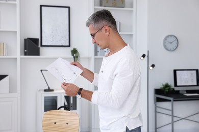 Photo of Architect holding paper sheet with engineering drawing in office