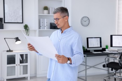 Architect holding paper sheet with engineering drawing in office