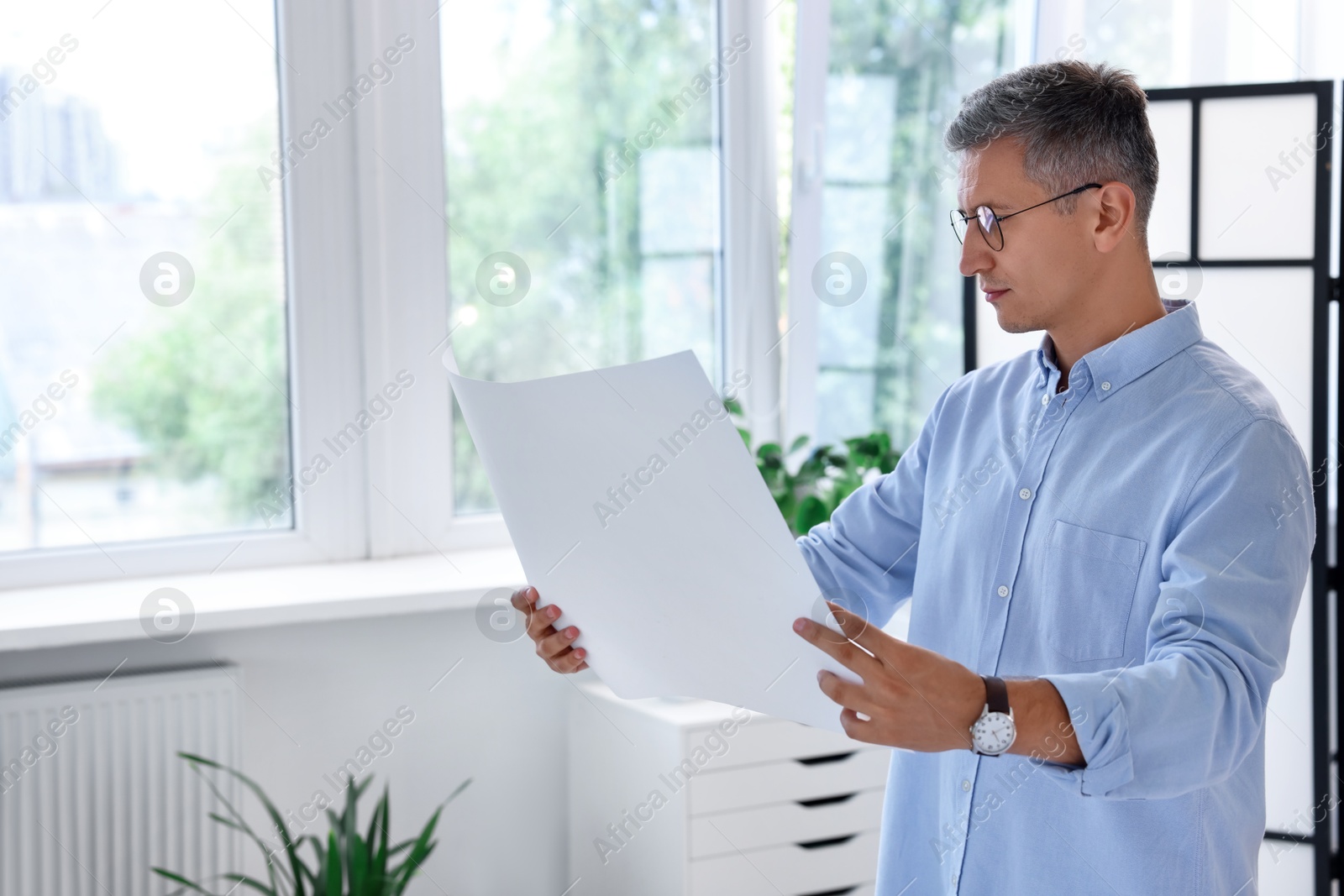 Photo of Architect holding paper sheet with engineering drawing in office