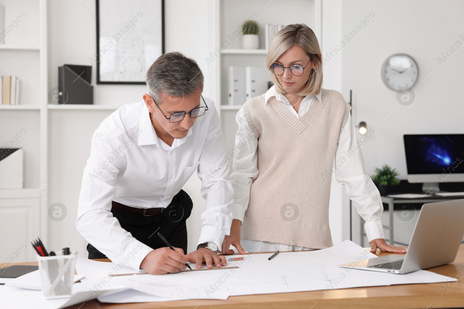 Photo of Architects making engineering drawing at wooden table in office