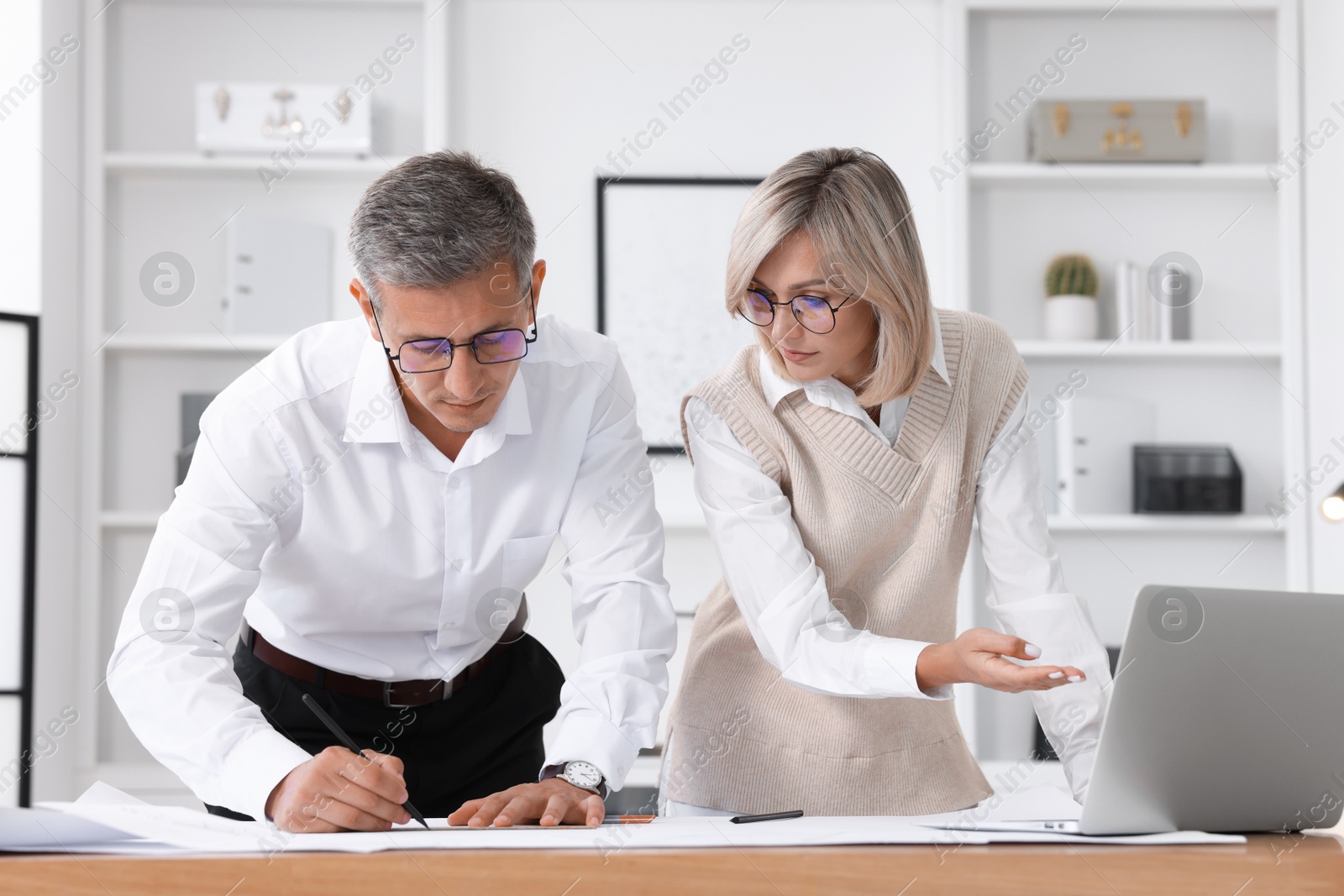 Photo of Architects making engineering drawing at wooden table in office