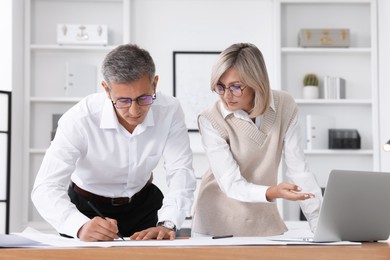 Architects making engineering drawing at wooden table in office