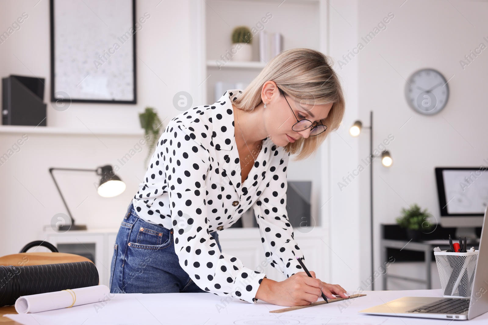 Photo of Architect making engineering drawing at wooden table in office