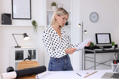 Architect holding paper sheet with engineering drawing in office