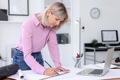 Architect making engineering drawing at table in office