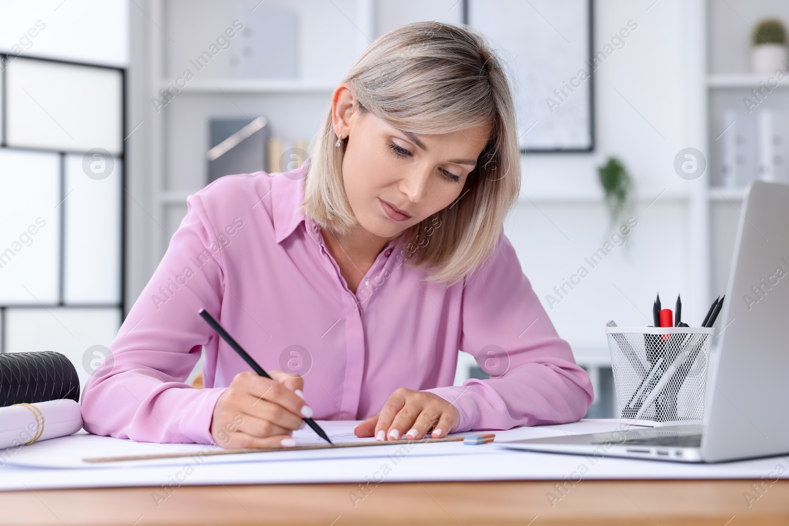 Photo of Architect making engineering drawing at wooden table in office