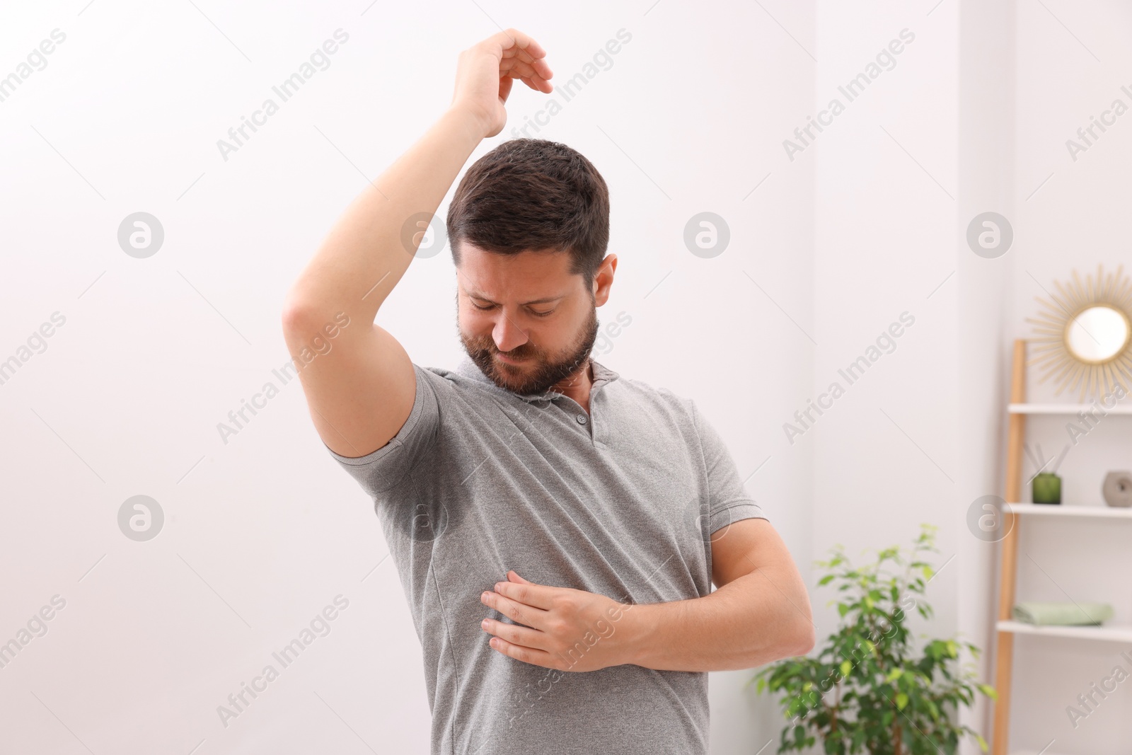 Photo of Emotional man in t-shirt before using deodorant at home