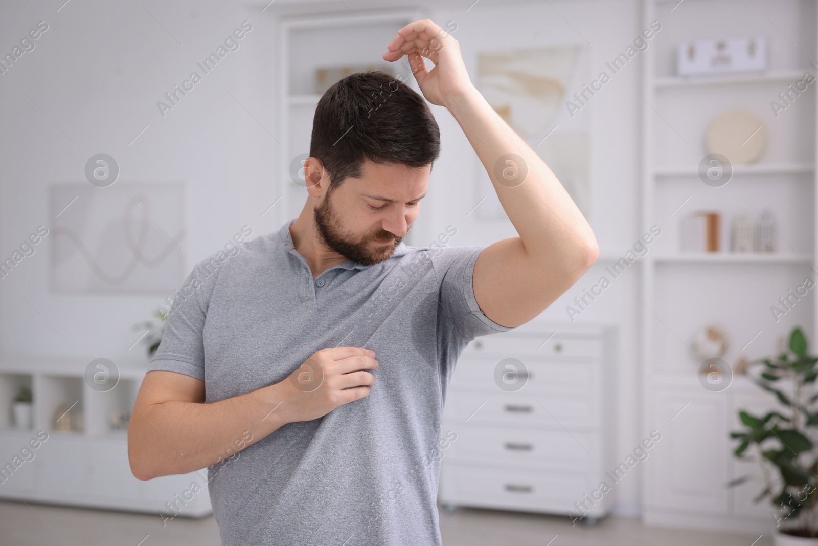 Photo of Emotional man in t-shirt before using deodorant at home