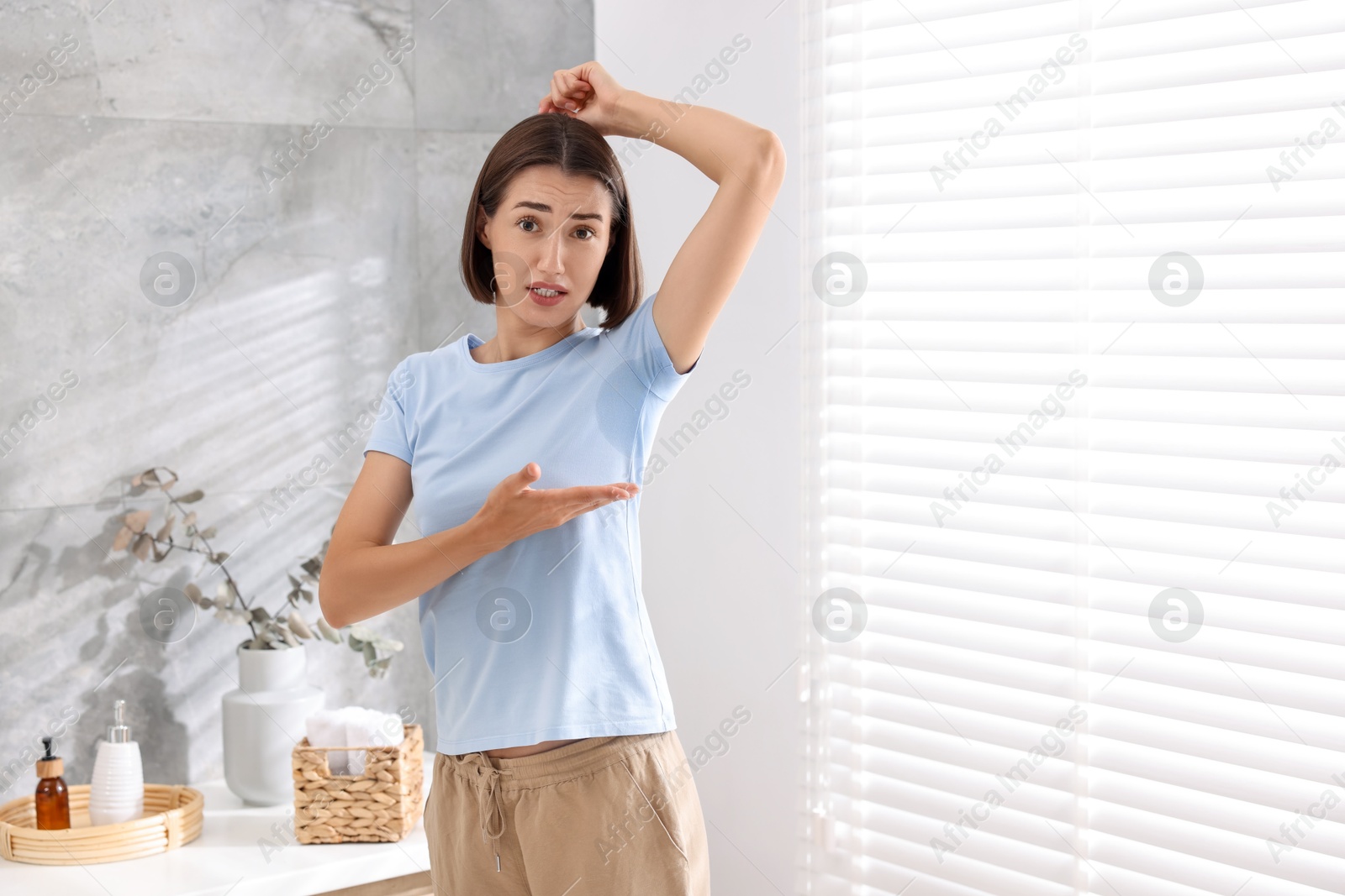 Photo of Emotional woman in t-shirt before using deodorant at home. Space for text