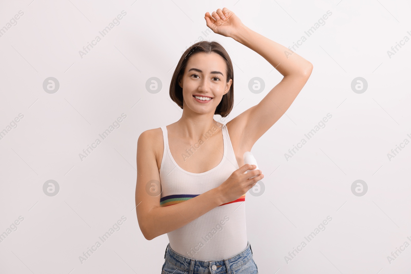 Photo of Smiling woman applying roll-on deodorant on white background