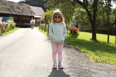 Cute little girl in stylish sunglasses outdoors