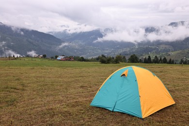 Photo of Camping tent on grass in mountains, space for text