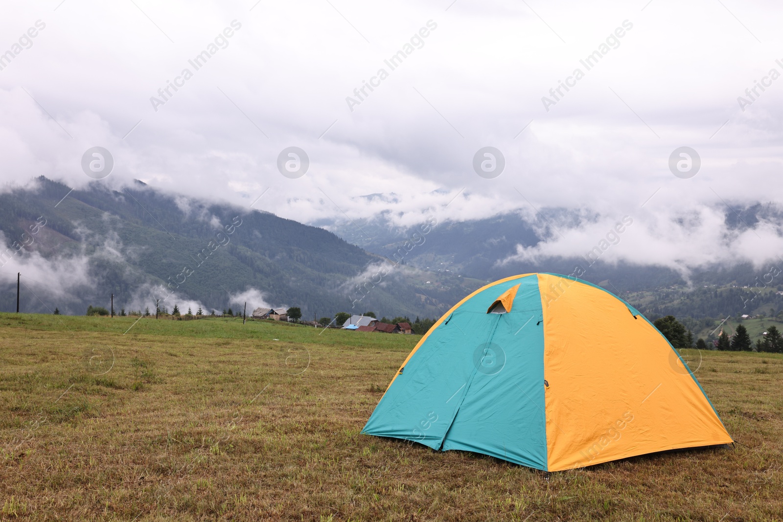 Photo of Camping tent on grass in mountains, space for text