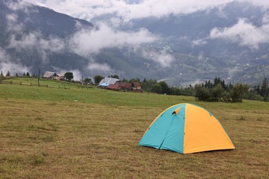 Photo of Camping tent on grass in mountains, space for text