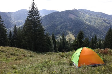 Photo of Camping tent on green grass in mountains