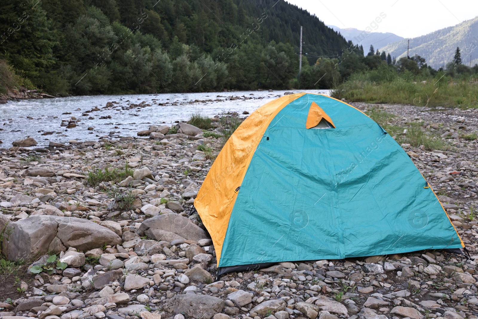 Photo of Camping tent on stones near river in mountains