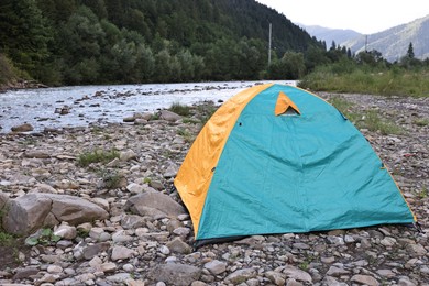 Photo of Camping tent on stones near river in mountains