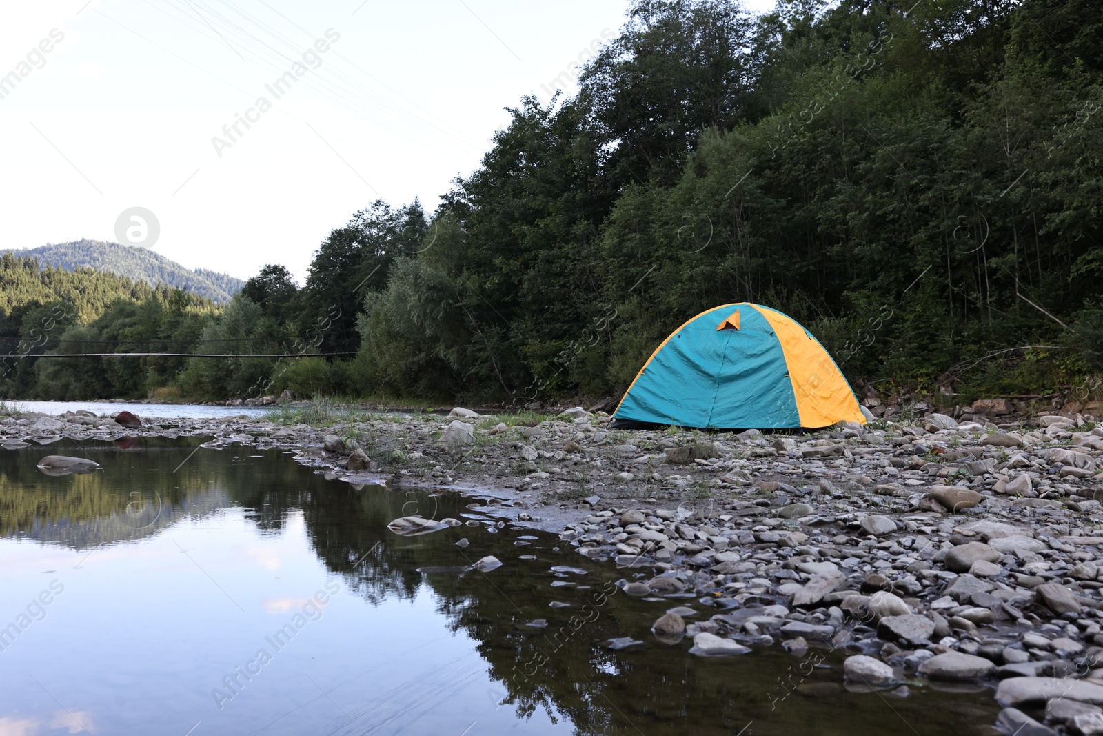 Photo of Camping tent on stones near river in mountains