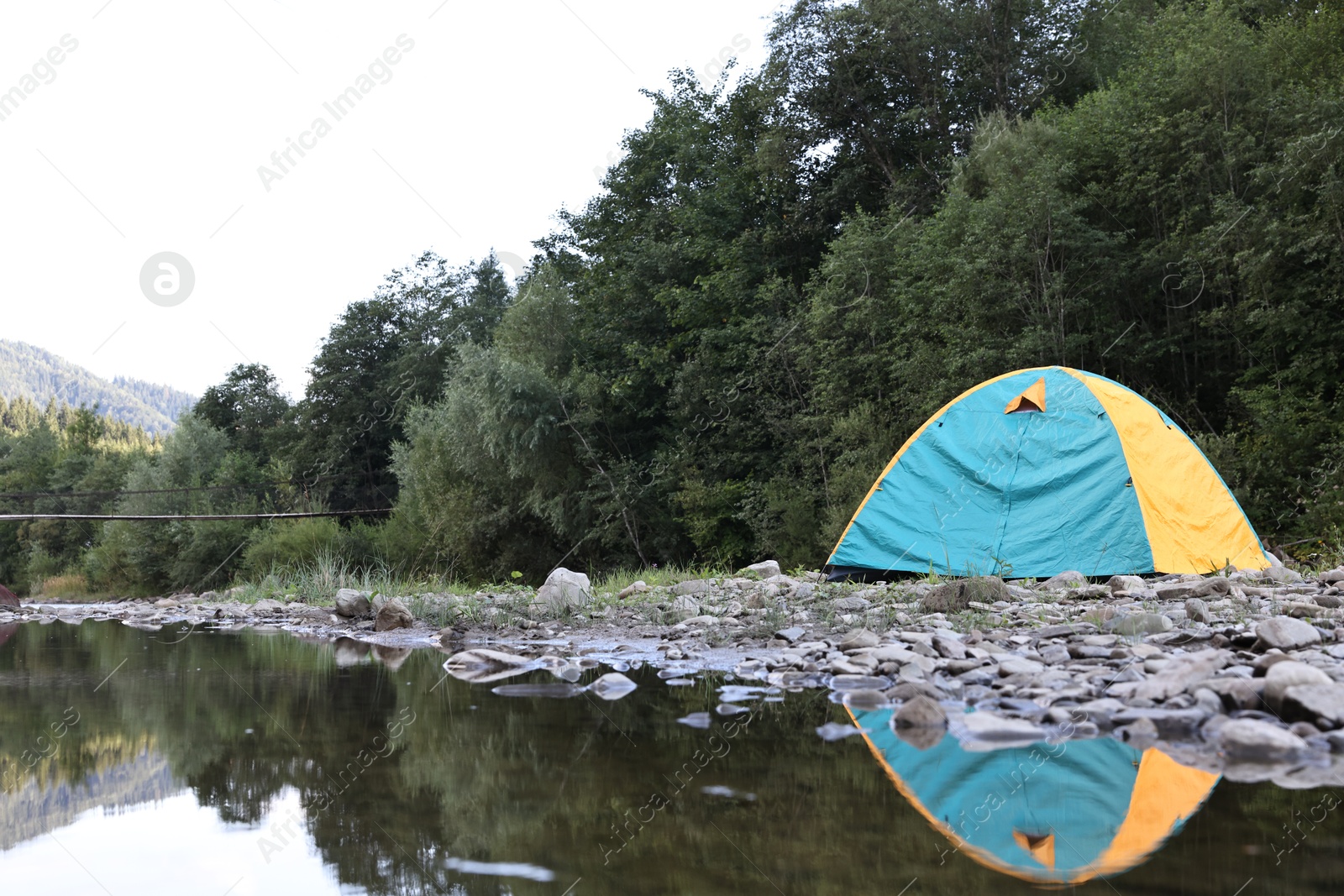 Photo of Camping tent on stones near river in mountains