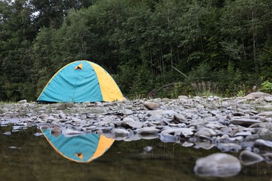 Photo of Camping tent on stones near river in mountains