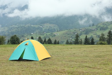 Photo of Camping tent on green grass in mountains, space for text