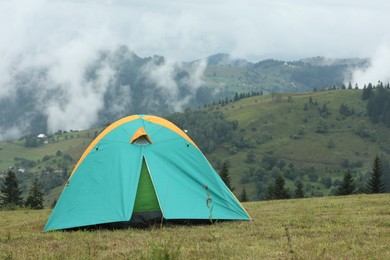 Photo of Camping tent on green grass in mountains