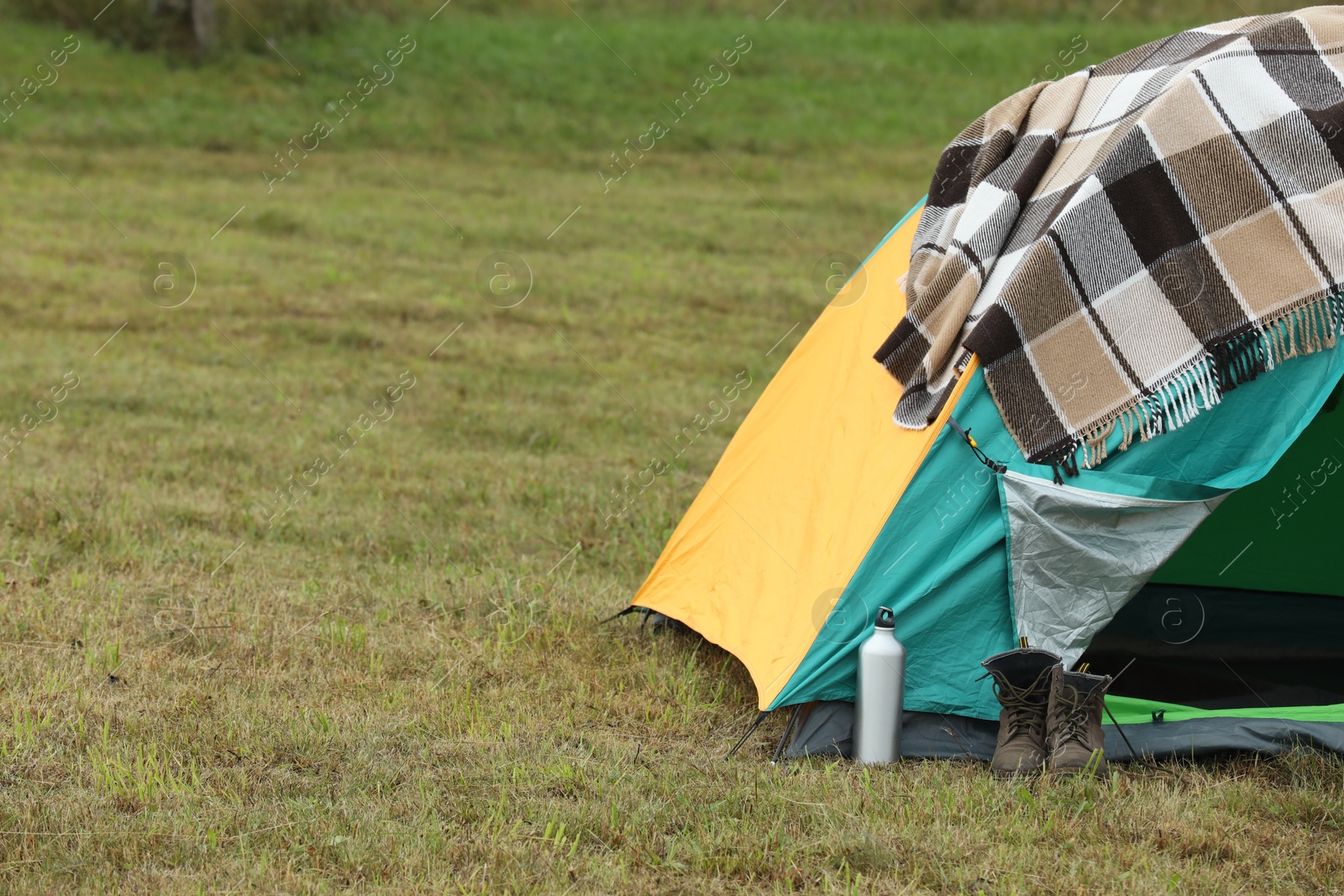 Photo of Camping tent and tourist stuff on green grass in mountains, space for text