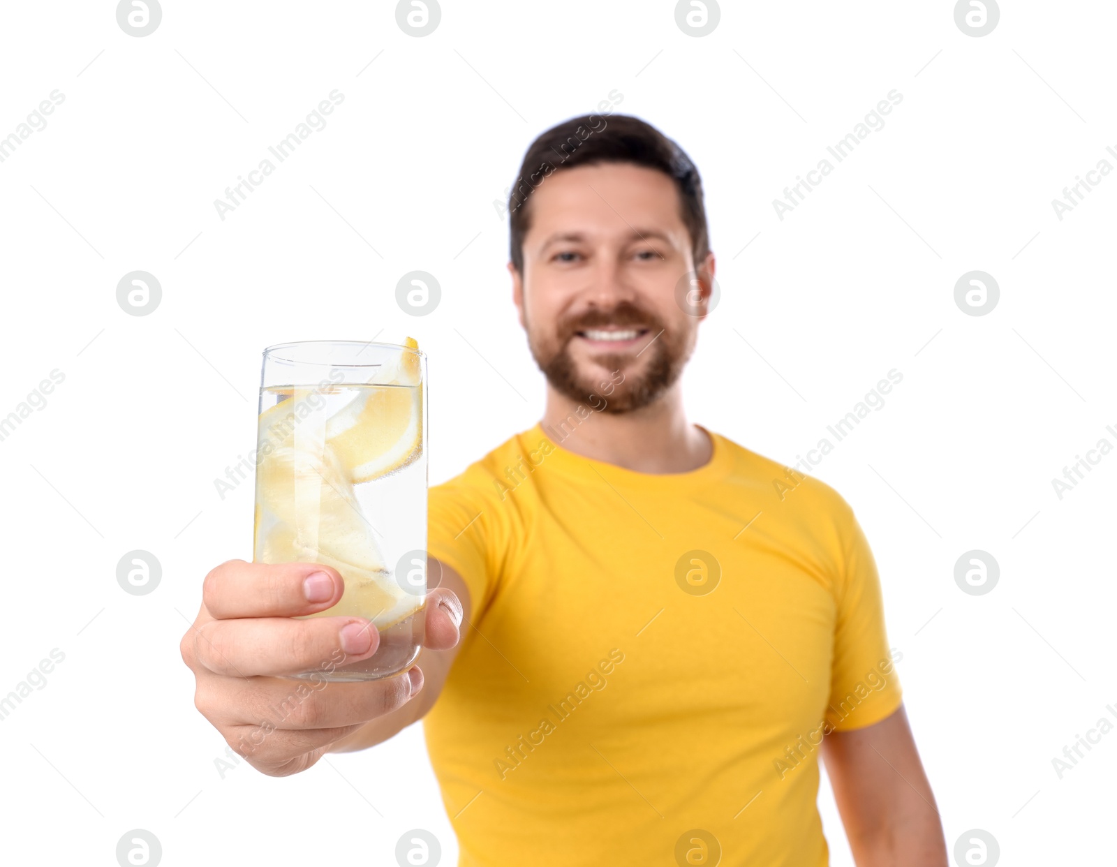 Photo of Happy man showing glass of water with lemon on white background, selective focus