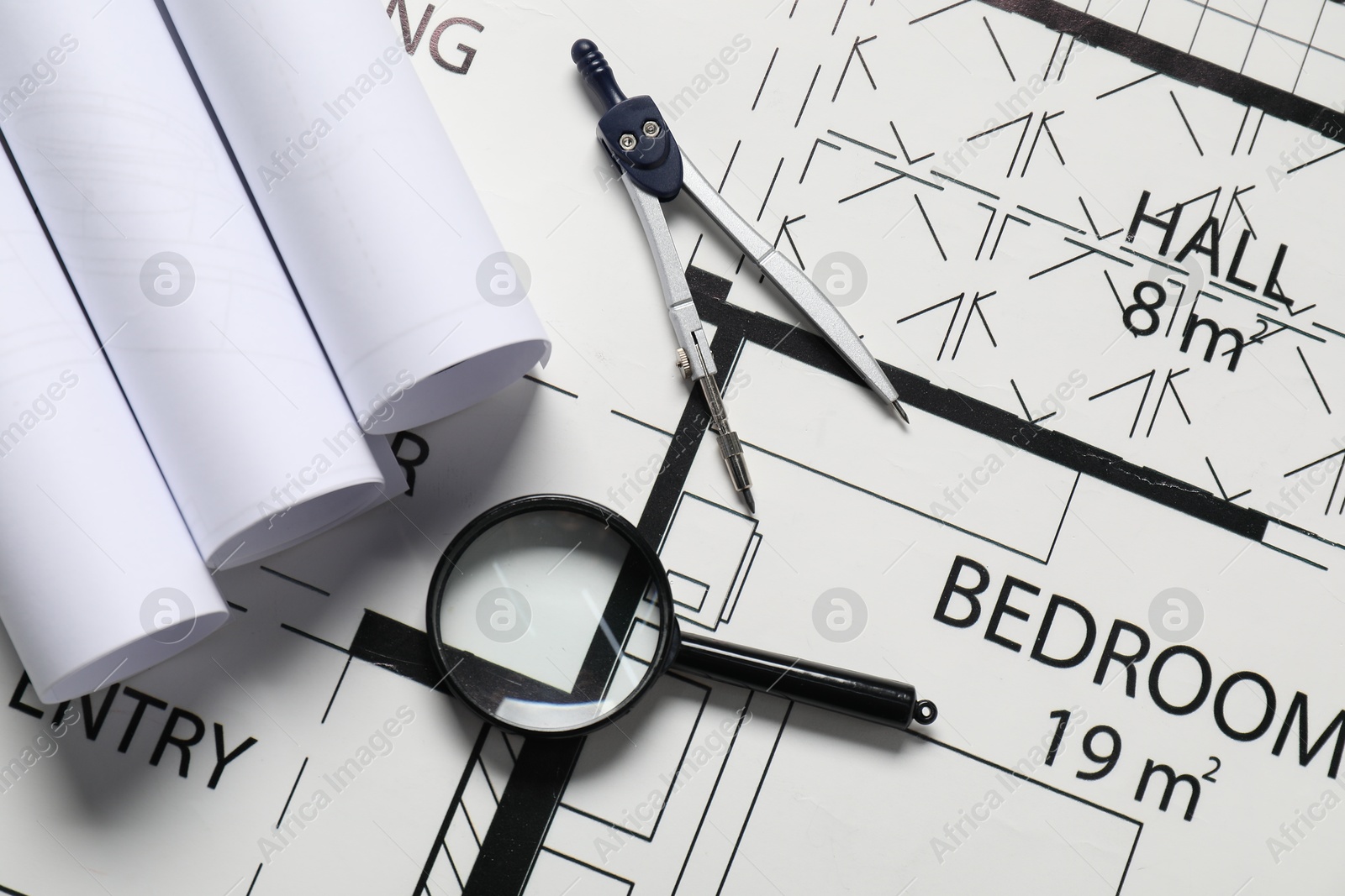 Photo of Dividers and magnifying glass on different engineering drawings, top view