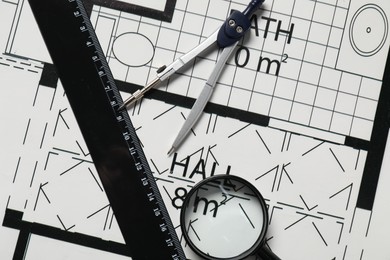 Photo of Dividers, ruler and magnifying glass on different engineering drawings, top view