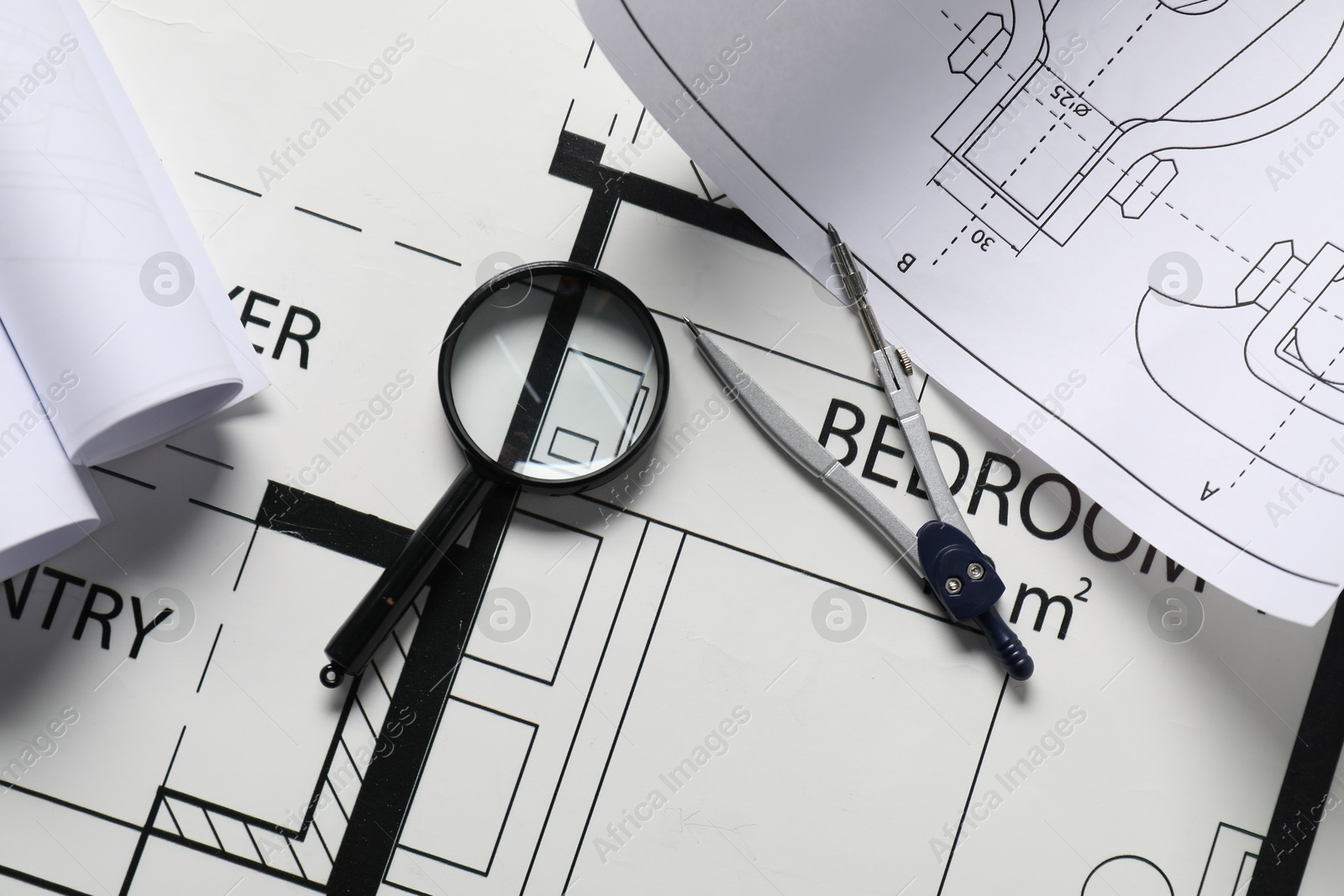 Photo of Dividers and magnifying glass on different engineering drawings, top view