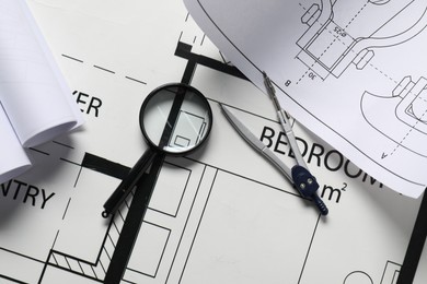 Dividers and magnifying glass on different engineering drawings, top view