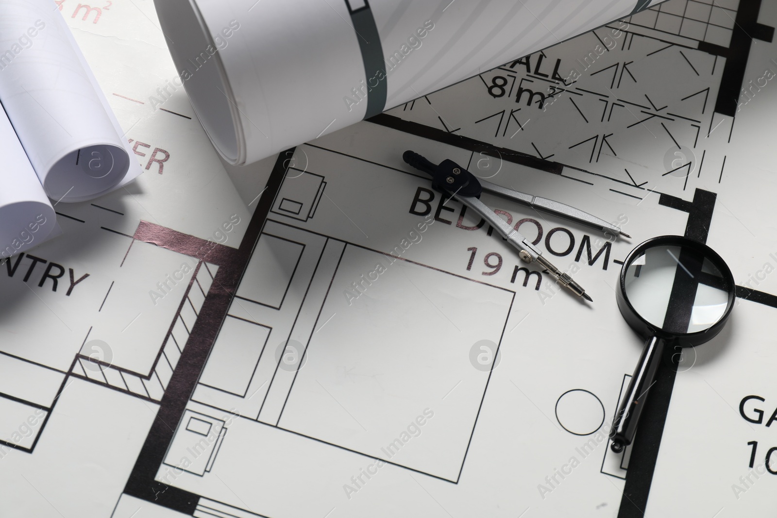 Photo of Dividers and magnifying glass on different engineering drawings