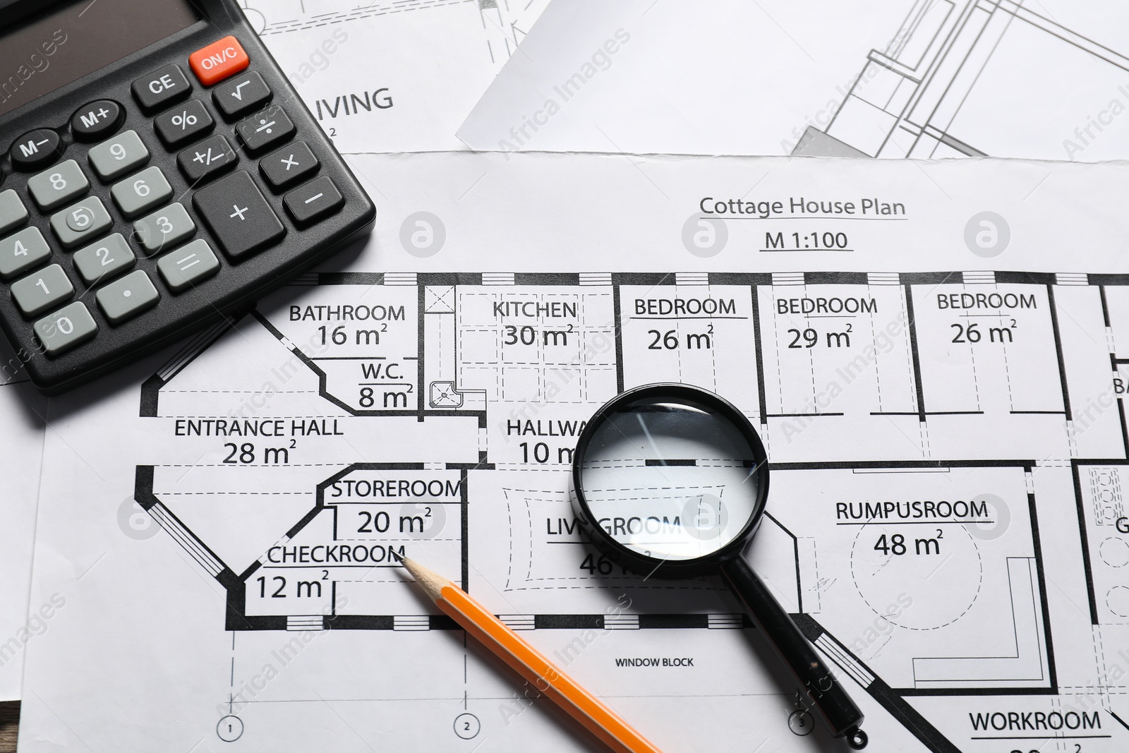 Photo of Calculator, pencil and magnifying glass on different engineering drawings, above view