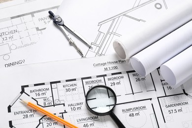 Photo of Dividers, pencil and magnifying glass on different engineering drawings, above view