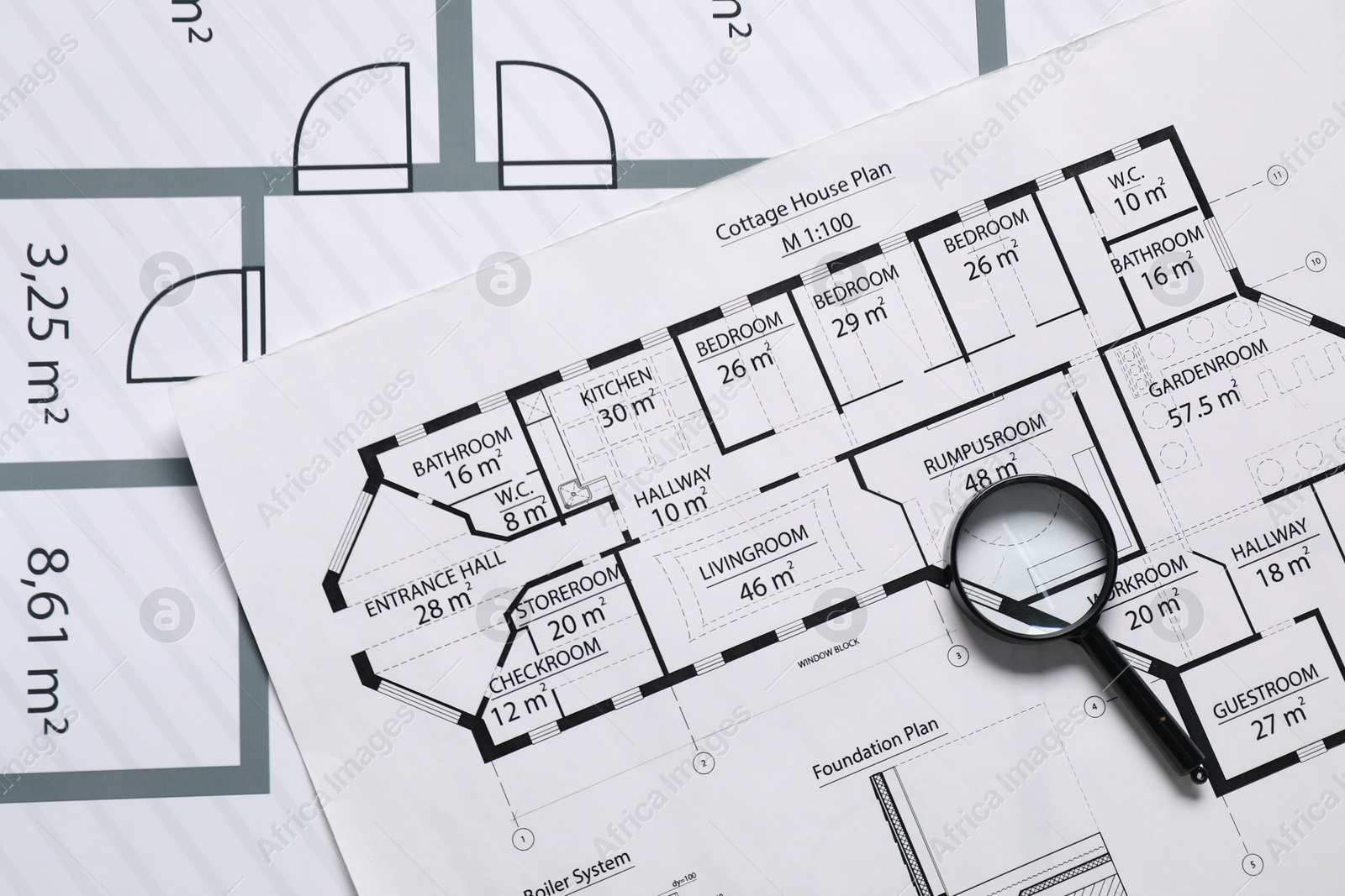 Photo of Magnifying glass on different engineering drawings, top view