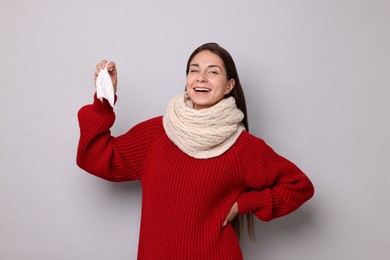 Smiling woman with tissue on grey background