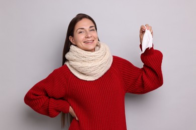 Smiling woman with tissue on grey background