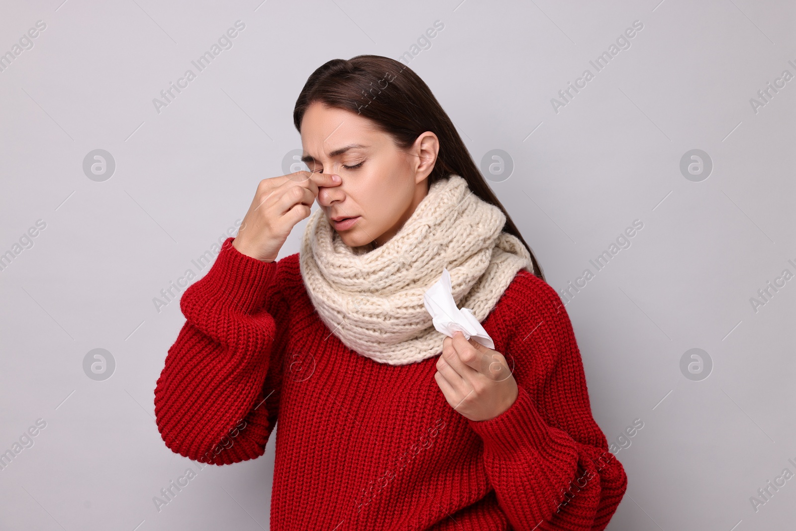 Photo of Sick woman with tissue on grey background. Cold symptoms