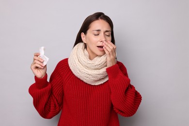 Photo of Sick woman with tissue on grey background. Cold symptoms