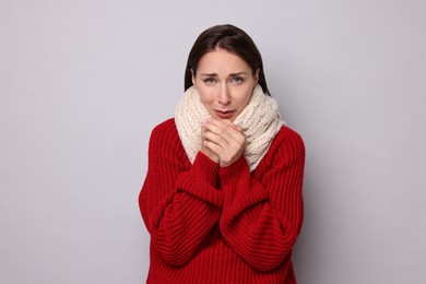 Sick woman suffering from cold symptoms on grey background