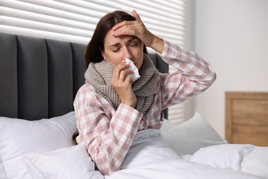 Photo of Sick woman with tissue in bed. Cold symptoms