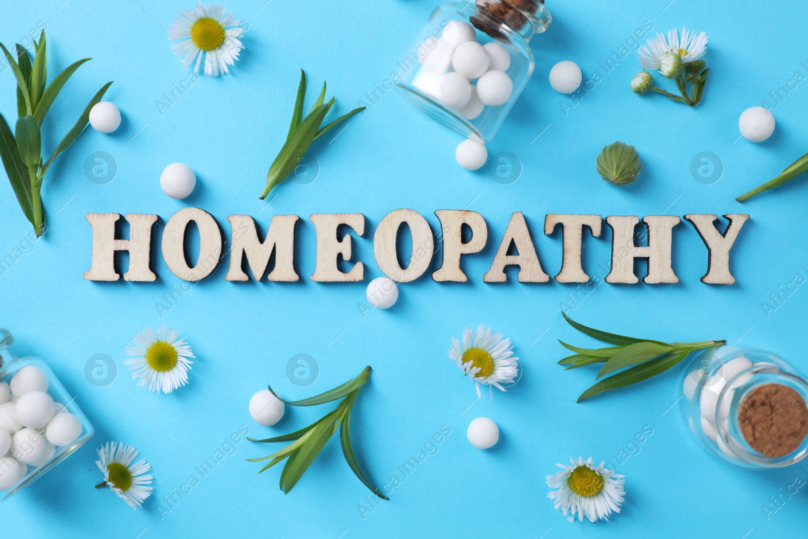 Photo of Word Homeopathy, chamomile flowers and pills on light blue background, flat lay