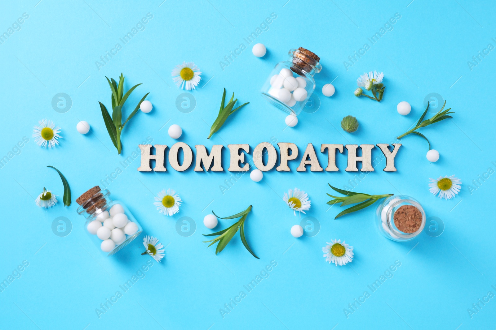 Photo of Word Homeopathy, chamomile flowers and pills on light blue background, flat lay