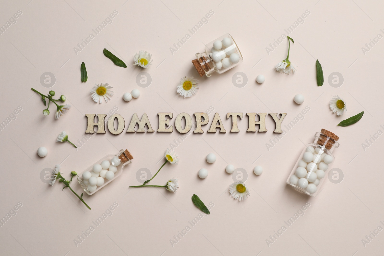 Photo of Word Homeopathy, pills and chamomiles on beige background, flat lay