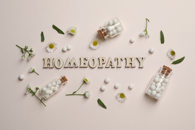 Photo of Word Homeopathy, pills and chamomiles on beige background, flat lay