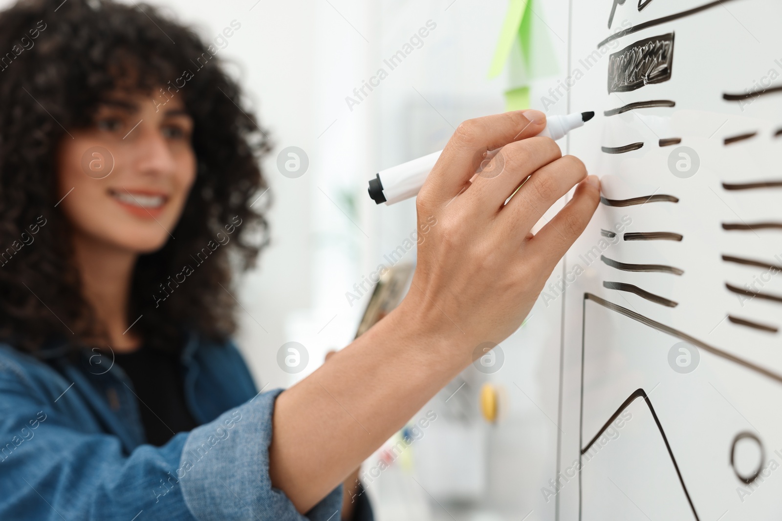 Photo of Developing UI design. Woman drawing website wireframe on whiteboard indoors, selective focus