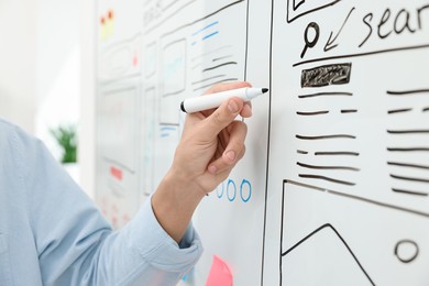 Photo of Developing UI design. Man drawing website wireframe on whiteboard indoors, closeup