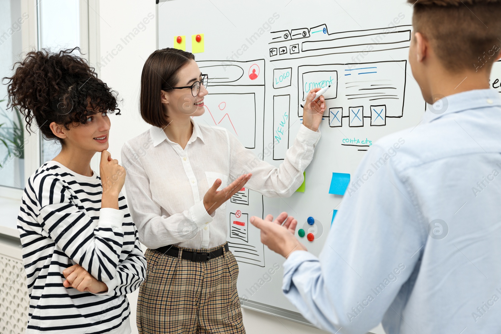 Photo of Developing UI design. People drawing website wireframe on whiteboard indoors