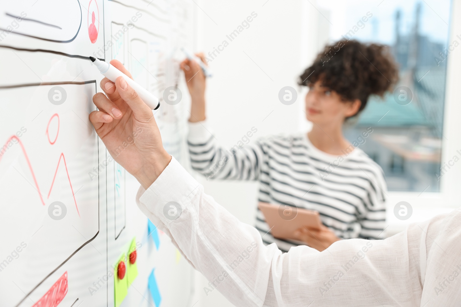 Photo of Developing UI design. Women drawing website wireframe on whiteboard indoors, selective focus